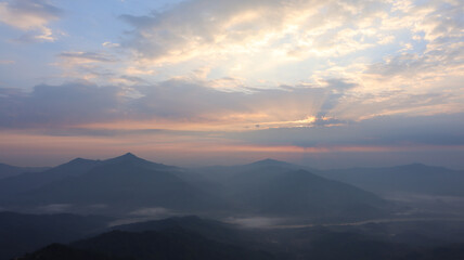 Morning view from the top of the mountain as the sun rises covered in mist created by the steam of the river below