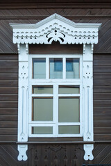 Obraz premium Old window with carved shutters on the facade of a wooden house