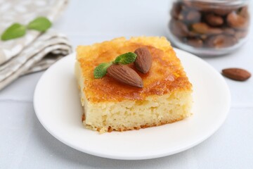 Slice of tasty semolina cake served on white tiled table, closeup