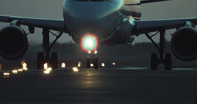 The wheels of a passenger plane travel along an illuminated runway. Flights on an airliner at night. High quality 4k footage