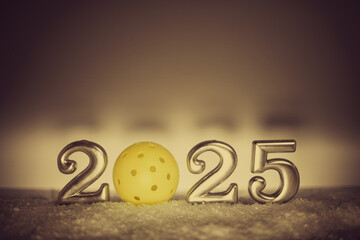 Closeup view of silver numbers 2025 New Year with pickleball and copy space. Cimenatic style backdrop