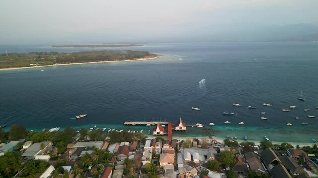 Aerial view of Gilli Trawangan with boats on clear turquoise water and a serene coastline, Bali, Indonesia.
