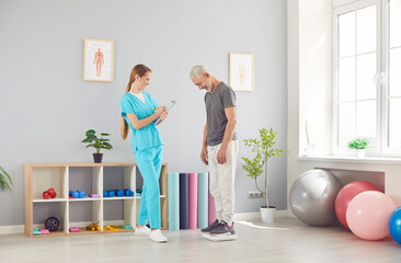 Female doctor physiotherapist or nurse weighing a senior patient using a scale during a...