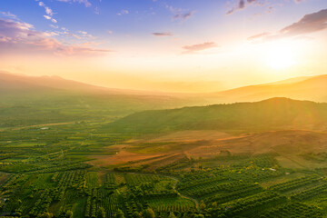 Fototapeta premium rustic landscape view of rural green valley in mountain hills with farms and gardens