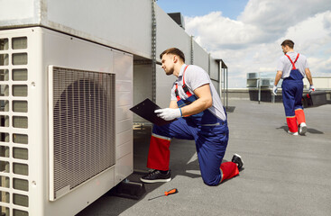 Caucasian male worker performing inspection, testing, and maintenance of an HVAC system on the...