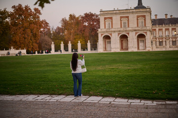 Obraz premium A tourist photographing the Royal Palace of Aranjuez in autumn, Madrid, Spain