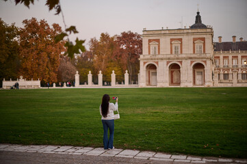 Obraz premium A tourist photographing the Royal Palace of Aranjuez in autumn, Madrid, Spain