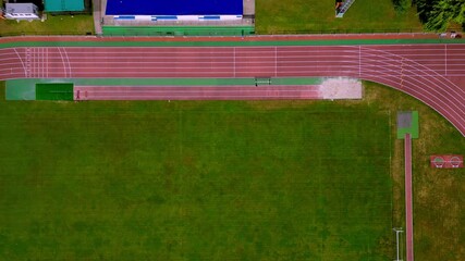 Aerial view of a running track and sports field with vibrant green grass and minimal activity, perfect for athletic and sports-themed projects.