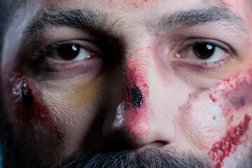Portrait of actor dressed as thriller film zombie with gore blood and bruises on face. Extreme close up of person costumed as undead corpse covered in wounds, professional makeup, studio background