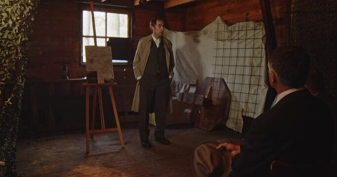 Wide dolly of a secret agent giving a briefing to a group of men during World War 2