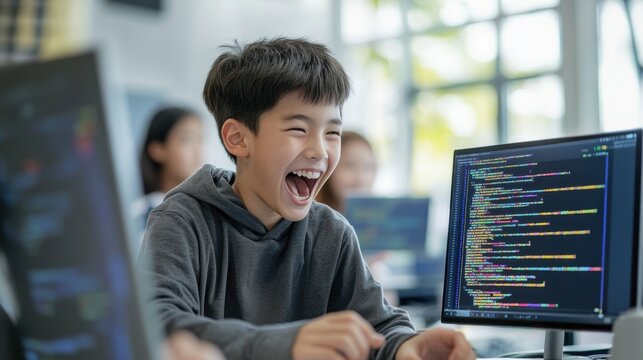 Asian teenage boy shows excitement as he learns new coding skills in technology class. Learning new things for kids. School classroom learning.