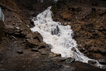 Cascading Waterfall Surrounded by Rocky Terrain in a Forested Environment