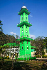 The towering green mosque minaret during the day