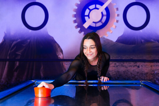 Gamer Girl Enjoying Air Hockey at Arcade with Futuristic Theme