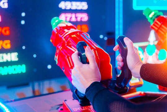 Hands Playing Arcade Shooting Game in a Neon-Lit Gaming Center