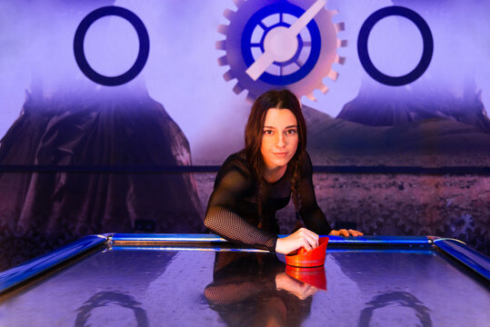 Young Woman Enjoying Air Hockey at Retro-Style Arcade