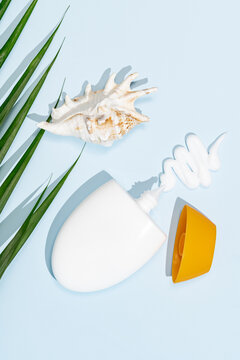 Sun protection cream with seashell on blue background
