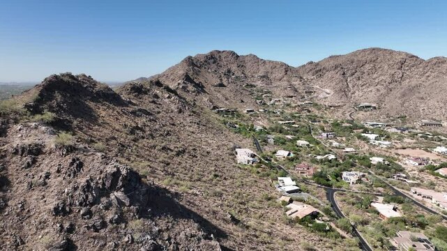 Aerial view of mummy mountain surrounded by beautiful rocky terrain and scenic valley with homes, Paradise Valley, United States.