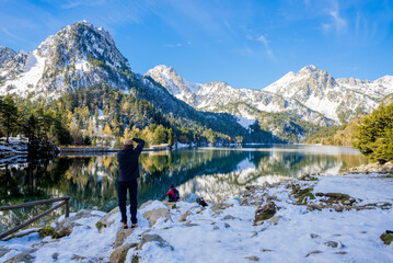 Photographer taking a photo of the snowy lake of Sant Maurici in the Aiguestortes National Park in...