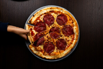 Pizza Salami mit Kinderhand - Kind greift nach einem Leckeren Stück Pizza 