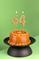 Number 64 birthday candle on a green background - Delicious cake with dulce de leche