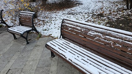 a wooden bench covered with snow in the park