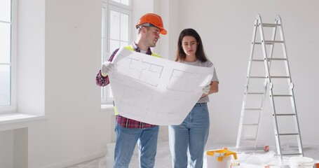 Builder and client or customer work together examining a detailed blueprint during a home renovation. Precise planning for the construction project, focusing on draft details for successful execution.