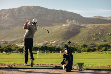 Man practicing his golf swing surrounded by beautiful outdoor mountain scenery