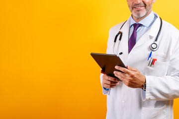 Nurse in blue lab coat holding tablet and stethoscope on yellow background.