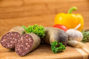Angeschnittene Blutwurst und ganze Rotwurst garniert mit Petersilie vor einem Holz Hintergrund