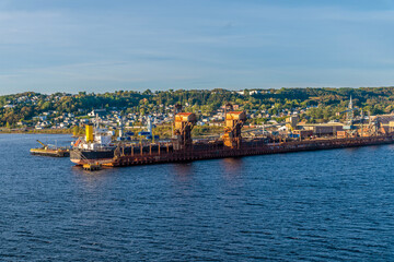 Naklejka premium A view from a ship along the side of the industrial port in the bay at Saguenay, Quebec in Canada in the fall