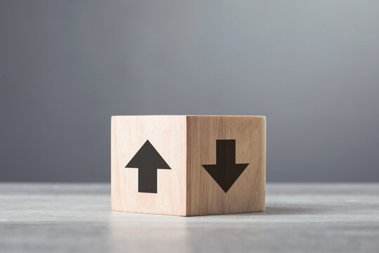 Upward and downward arrows alongside a question mark on wooden blocks, symbolizing the concept of decision-making. Represents the uncertainty and choices involved in selecting the right path forward