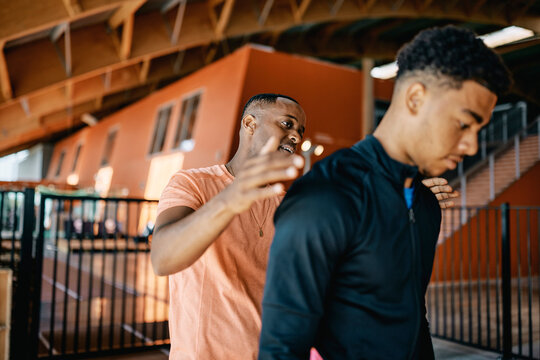 Smiling trainer giving a fit young man a pat on the back after a workout session together at the gym