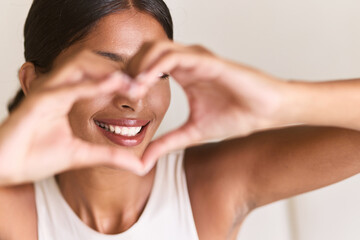 Teeth Whitening. Woman Creating Heart Shape With Hands, Radiating Happiness And Positivity. Natural Beauty With Emphasized White Teeth And Engaging Expression.