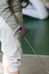 A hand in fencing costume holding an epee