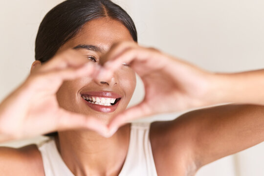 Dental Care. Woman Expressing Happiness And Self-Love With Heart-Shaped Hands. Bright Smile Reflects Confidence, Positive Energy, And Personal Connection.
