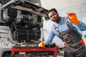 Mechanic holding spare parts for truck service.