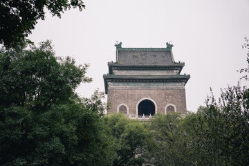 Fototapeta premium Beijing Bell Tower among the trees on a cloudy day of autumn, China
