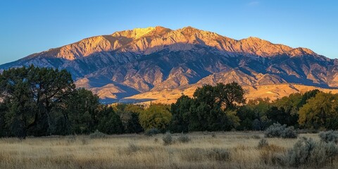 Fototapeta premium Early morning view of the mountains with the sun rising behind them, casting a golden glow on the landscape.