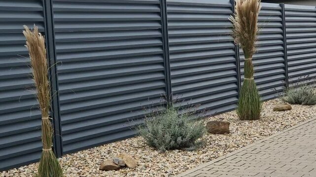 metal fillings of the fence with an underlay of concrete blocks. A metal aluminum fence will provide privacy around the garden. horizontal slats cover well. flower bed, perennial