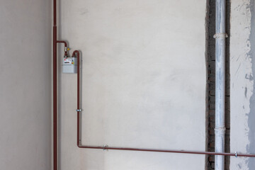 Gas counter with gas pipes in a corner of new unfinished apartment or house.