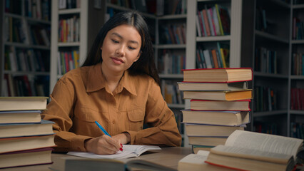 Focused Asian woman girl student ethnic female bookworm reader reading book in university library...