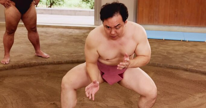 Warm up, sumo and wrestling with Japanese people in arena for training, shiko ritual and tournament. Festival, competition and game with asian men in dohyo ring of temple for culture and sports