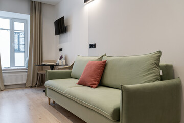 a bright living room with a soft green sofa, a TV and a table. Cozy relaxed atmosphere. decorative cushion on the sofa