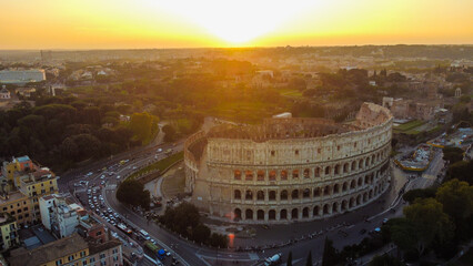 Visão aérea do Coliseu de Roma ao pôr do sol, capturando a luz dourada sobre as antigas ruínas romanas. Uma paisagem deslumbrante que reflete a história e o charme de Roma, Itália