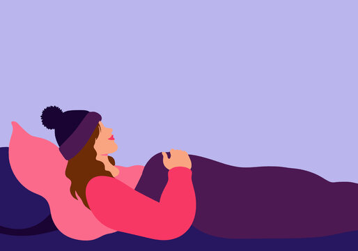 Woman with blanket and knit hat sleeping on bed against colored background
