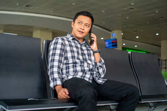 Asian man using mobile phone in airport waiting area. Male Tourist calling with his phone while waiting for departure in the airport.