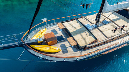 A gulet ship anchored in crystal-clear waters, surrounded by lush green hills and a serene coastal...