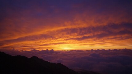 Fiery sunset over a sea of clouds, viewed from a mountain peak.