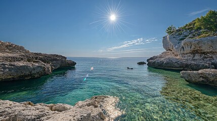 Fototapeta premium Idyllic cove with crystal-clear turquoise water, sunlit rocks, and a bright summer sky.